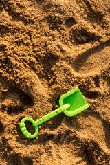 Fototapeta na wymiar Green shovel on sand texture