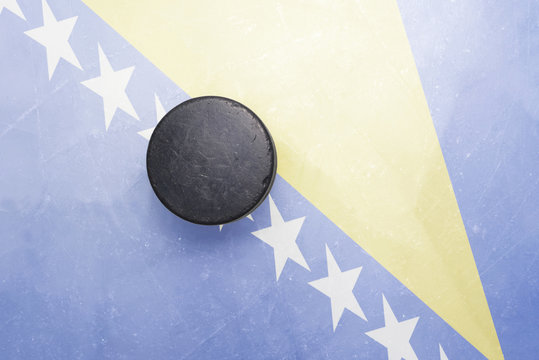 old hockey puck is on the ice with bosnia and herzegovina flag