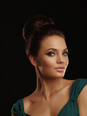 Fototapeta premium Portrait of a young beautiful girl with collected hair and expressive make up on the black background
