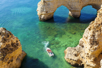 Boot mit Touristen, die die Höhlen in der Nähe des Strandes besuchen (Praia da