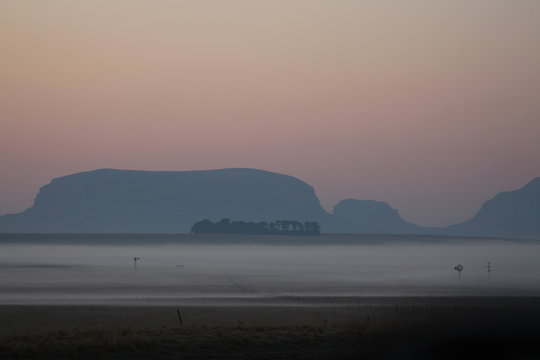 cold early morning on the farm overlooking fog filled valley with windmill pump mountains in the background