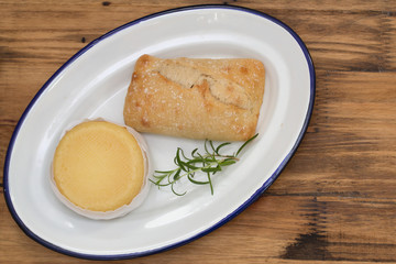 cheese with bread on white dish on brown wooden background