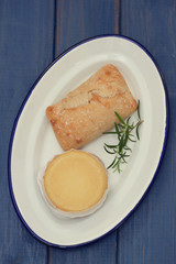 cheese with bread on white dish on blue wooden background