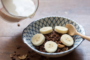 granola with banana in a bowl on wooden table