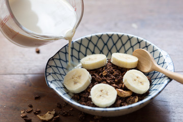 granola with banana in a bowl on wooden table