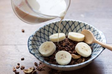 granola with banana in a bowl on wooden table