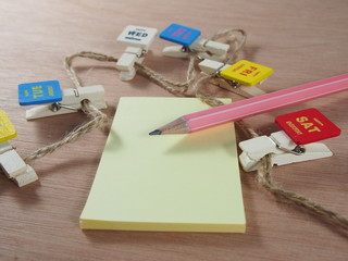 Stationery, pink pencil, sticky paper with wooden clips as business days