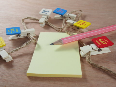 Stationery, pink pencil, sticky paper with wooden clips as business days
