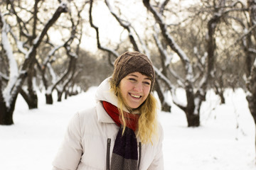 Fototapeta na wymiar Young beautiful girl close up in winter park enjoys snow fell