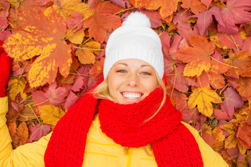 Happy woman laying in red leaves 