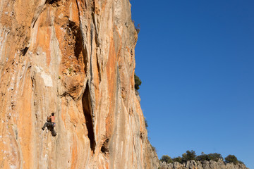 Young male climber hanging by a cliff.