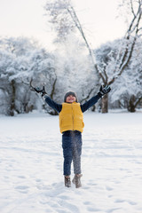 boy jumping throwing snow up near the forest