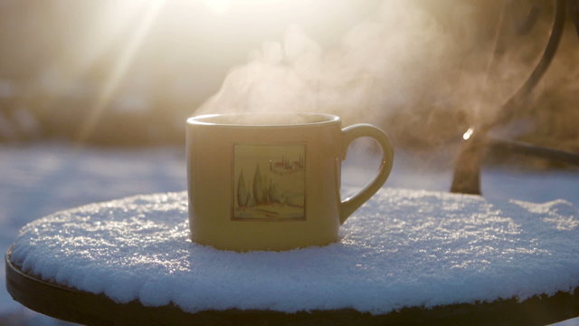Cup with hot tea against the sun in the winter