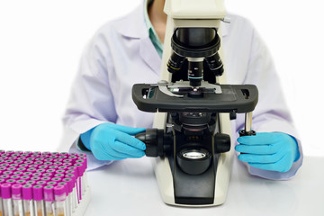 Medical technologist analyzing blood smear by using microscope
