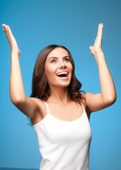 Happy gesturing woman looking up, over blue
