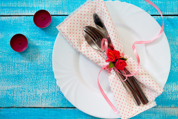 Romantic table setting - plate, knife, fork, spoon and napkin on