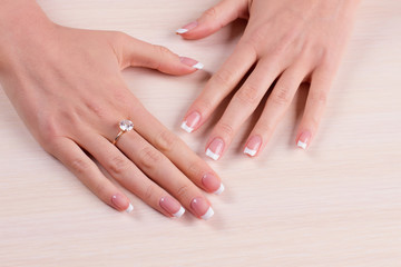 Diamond ring on finger. Gentle french manicure.