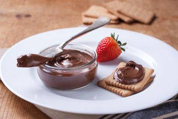 Chocolate sweet melting nougat cream on cookies with strawberries on a white plate. Closeup..