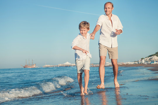 Father with son running together on the sea surf line