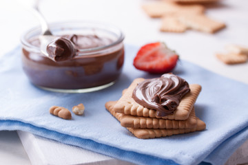 Chocolate sweet melting nougat cream on cookies with strawberries on a white plate, closeup, selective focus.