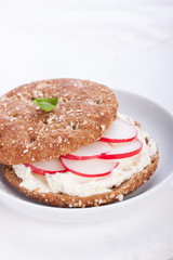 .Sandwich with wholewheat bread, cottage cheese, radish and basil on a white plate, closeup, selective focus.