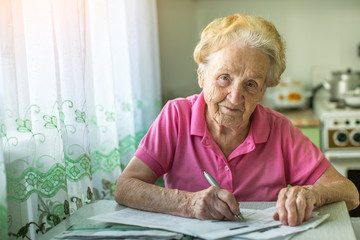 An elderly woman fills the bill for payment of utility services.