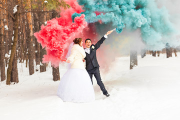 Wedding couple with color smoke in the winter park. Colour bomb