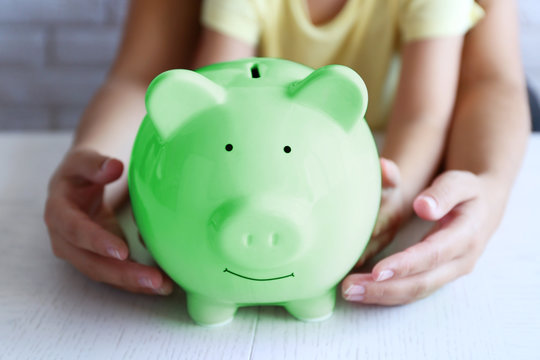 Little girl with her mum and pig  moneybox closeup