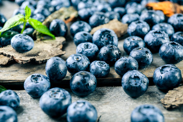 Tasty ripe blueberries with green leaves on wooden table close up