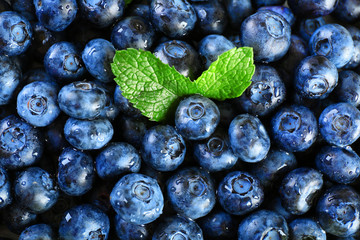 Tasty ripe blueberries with green leaves close up