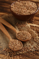 Buckwheat seeds in wooden spoon on a brown wooden table