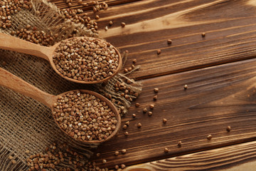 Buckwheat seeds in wooden spoon on a brown wooden table