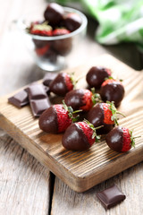 Fresh strawberries dipped in dark chocolate on grey wooden backg