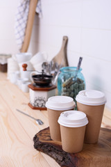 Fototapeta na wymiar Coffee cups for take away, various sizes, and kitchenware on wooden lunch counter.