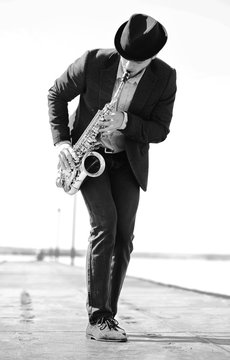 Young man playing on saxophone on the riverside