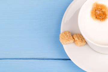 Cappuccino and cane sugar on a blue table