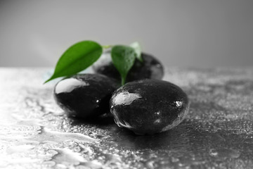 Composition of pebbles with leaf on the table against grey background