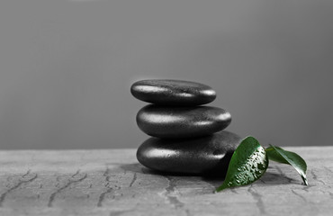 Pile of pebbles with leaf on the table against grey background