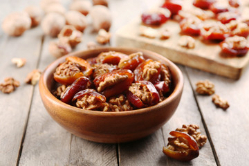 Walnut and date fruit in bowl on wooden table, close-up