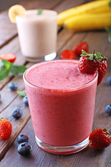 Glasses of fresh cold smoothie with fruit and berries, on wooden background