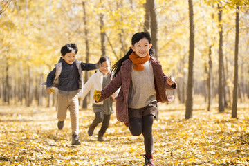 Three children running in autumn woods