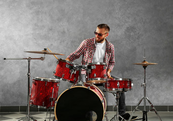 Fototapeta premium Musician playing the drums on grey wall background