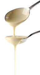 Condensed milk pouring from spoons, isolated on white