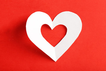 Cut out white paper heart on red background
