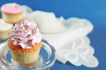 Tasty cupcakes on stand, on color wooden background