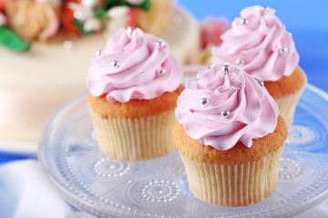 Tasty cupcakes on stand and cake, on table, on color background