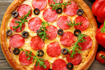 Tasty pizza with salami and red vegetables on wooden background, close up
