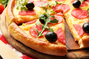 Delicious tasty pizza with salami and olives on wooden background, close up