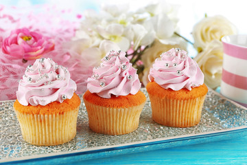Tasty cupcakes on plate, on color wooden background