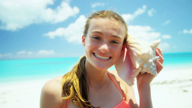 Portrait of a Caucasian female teenager on a beach with a conch shell